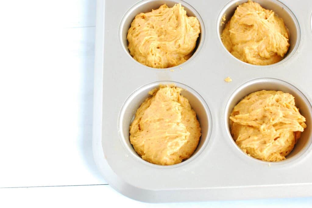 Pumpkin muffin batter poured into a muffin tin.