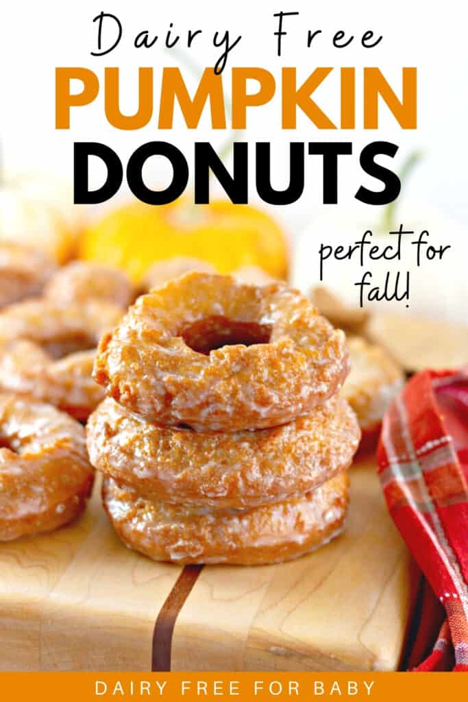 A stack of three dairy free pumpkin donuts on a wooden cutting board.