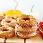 Glazed dairy free pumpkin donuts on a wooden cutting board.