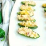 Vegan jalapeno poppers on a white plate next to a napkin.