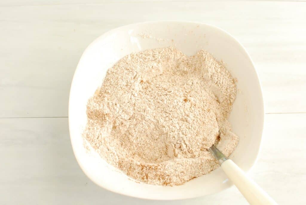 Flour, cinnamon, baking powder, and salt mixed together in a bowl.