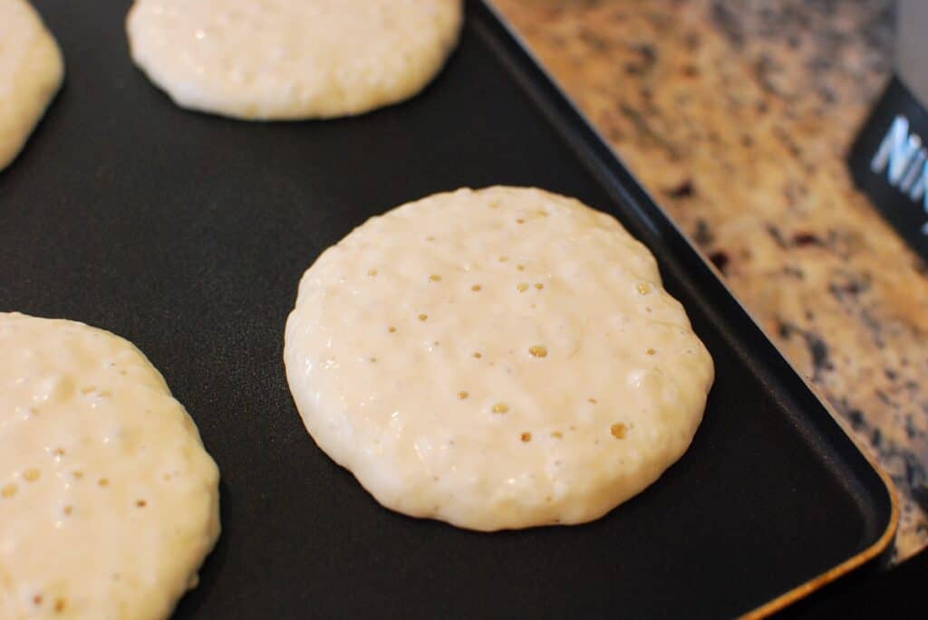 A pancake on a griddle that's ready to be flipped.