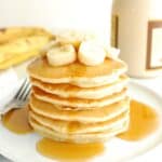 A stack of banana pancakes topped with maple syrup on a plate.