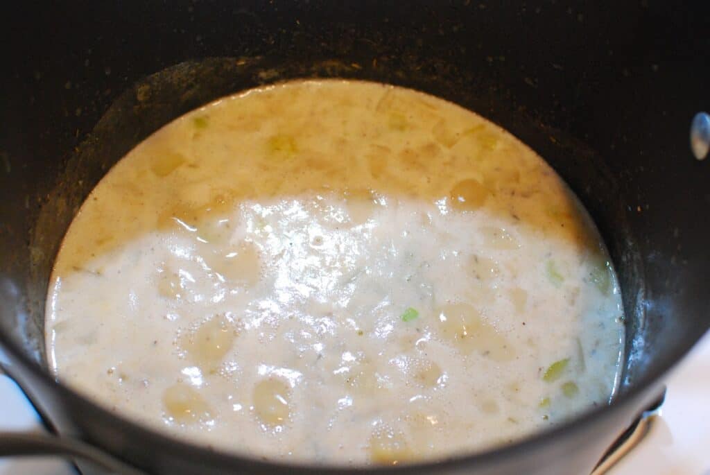 Potatoes cooking in a pot of clam chowder.