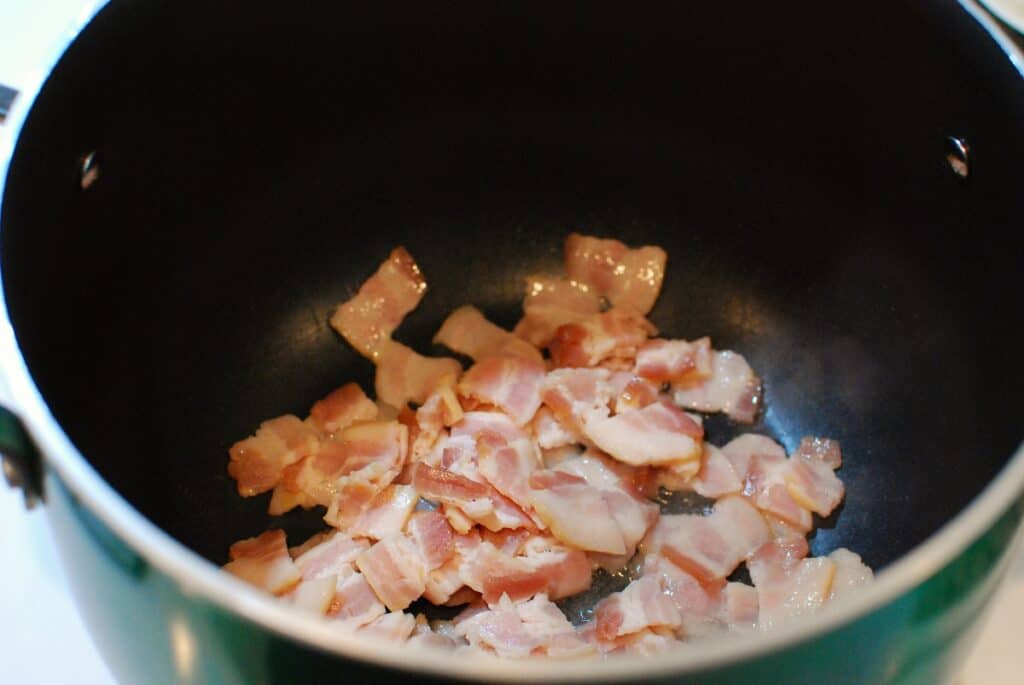 Chopped bacon cooking in a pot.