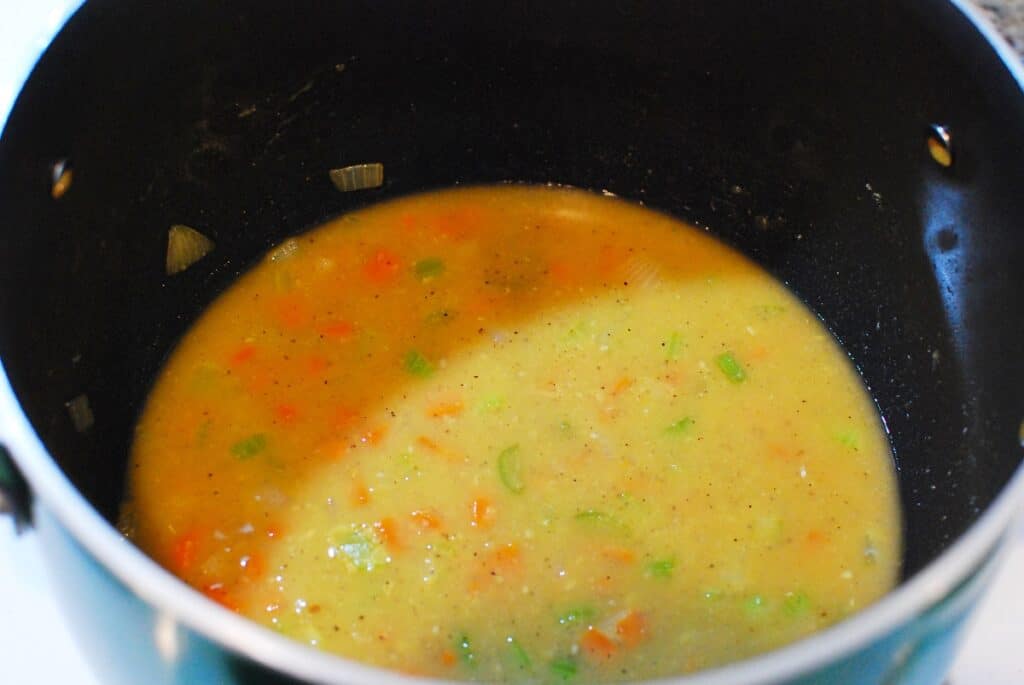 A pot of soup after chicken broth has been added.