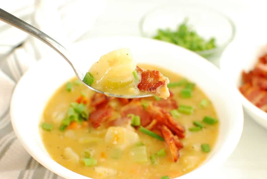 A spoonful of dairy free potato soup, hovering over the bowl.