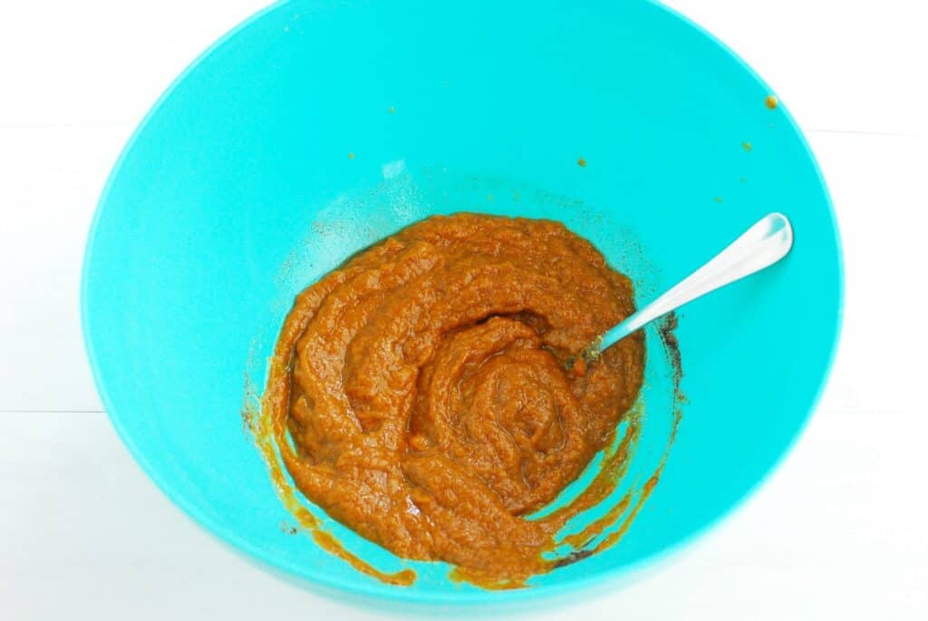 A bowl with pumpkin, brown sugar, vanilla, pumpkin spice, oil, and egg whisked together.