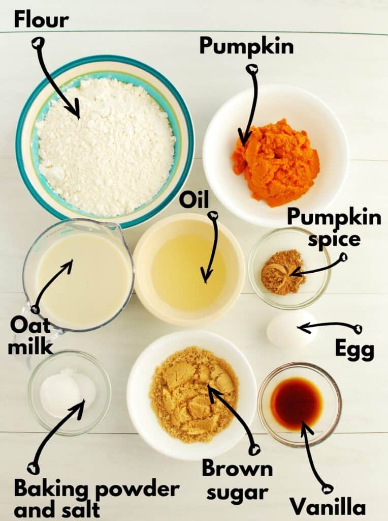 Bowls of ingredients, including flour, oat milk, baking powder, salt, brown sugar, oil, pumpkin, pumpkin spice, egg, and vanilla.