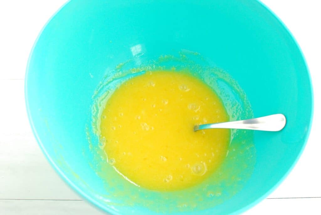 Egg yolks mixed with granulated sugar in a bowl.