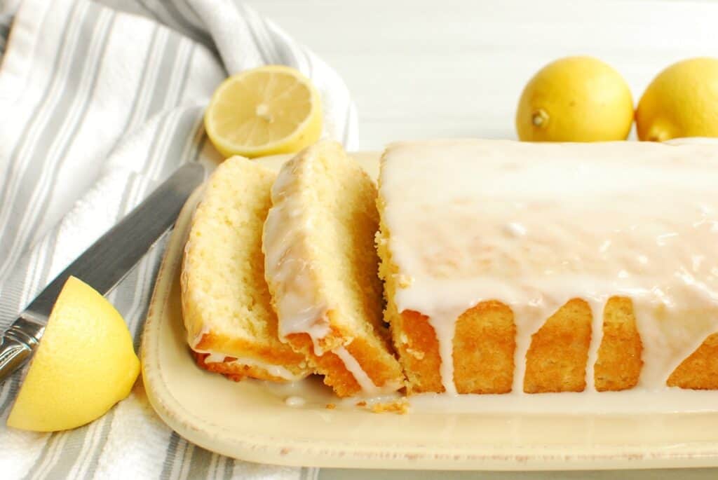 A loaf of dairy free lemon pound cake with several slices cut into it.