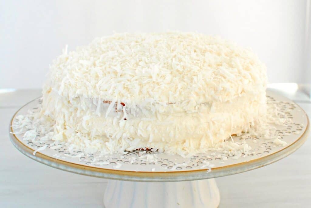 A dairy free coconut cake on a cake stand.