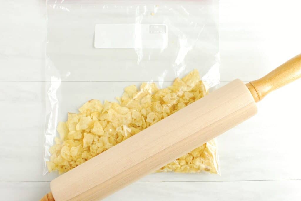 A ziptop bag with potato chips and a rolling pin on top.