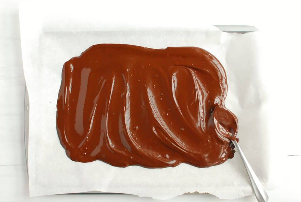 Melted chocolate spread onto a baking sheet with parchment paper.