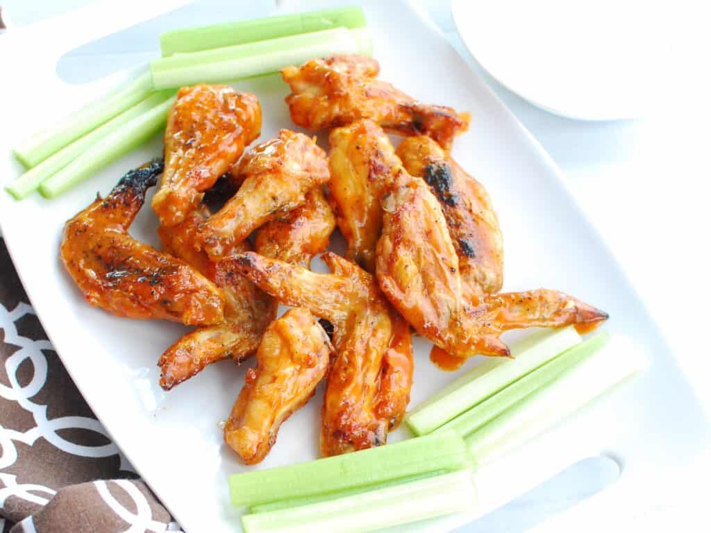 Wings tossed in buffalo sauce on a white plate.