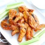 A plate with dairy free chicken wings and celery.