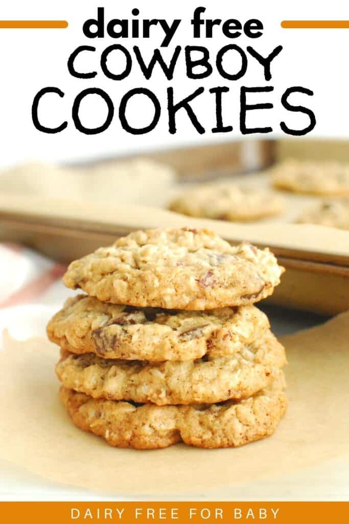 Several dairy free cowboy cookies stacked on top of each other with a baking sheet in the background.