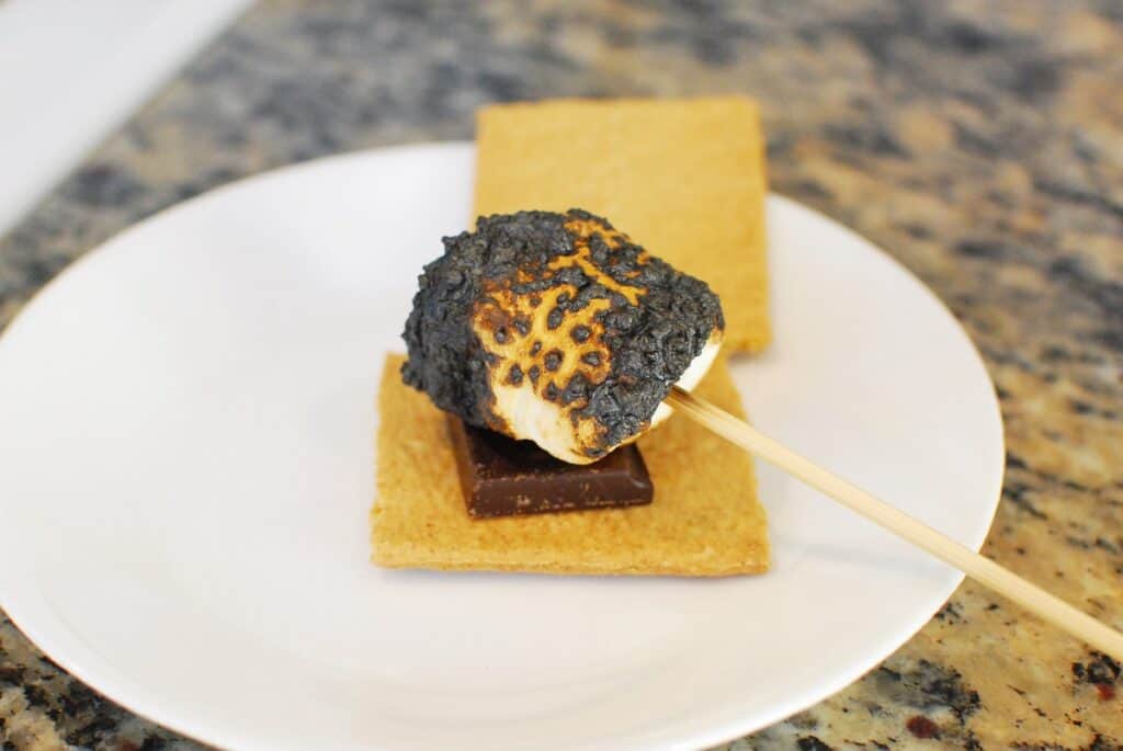 Placing a marshmallow on a graham cracker with chocolate.