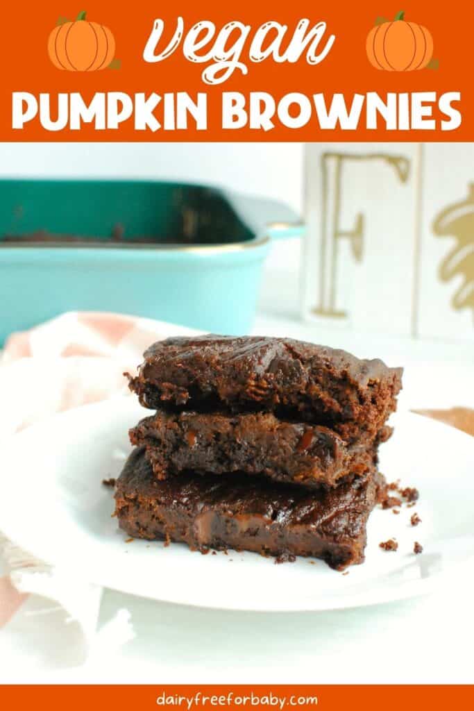 Three vegan pumpkin brownies on a plate next to a napkin and a fall sign.