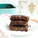 Several fudgy vegan pumpkin brownies on a plate with a napkin next to it.