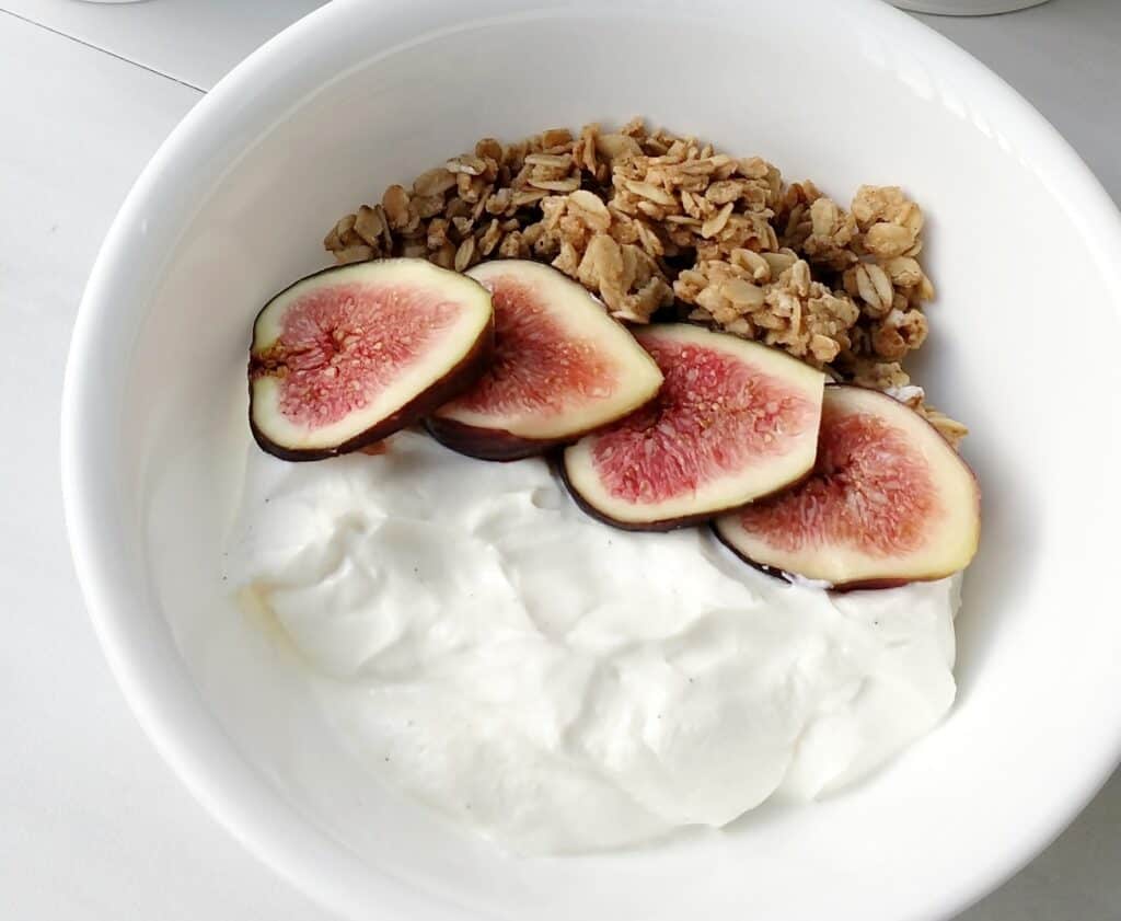 A bowl of dairy free yogurt topped with figs and granola.