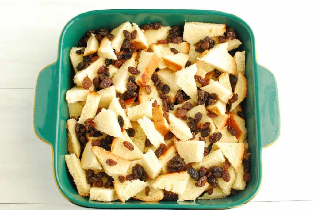 Cubed bread and raisins placed in a baking dish.