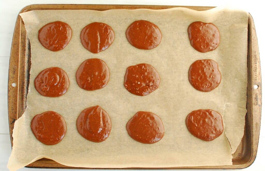 Unbaked brownie cookie batter on a baking sheet lined with parchment paper.