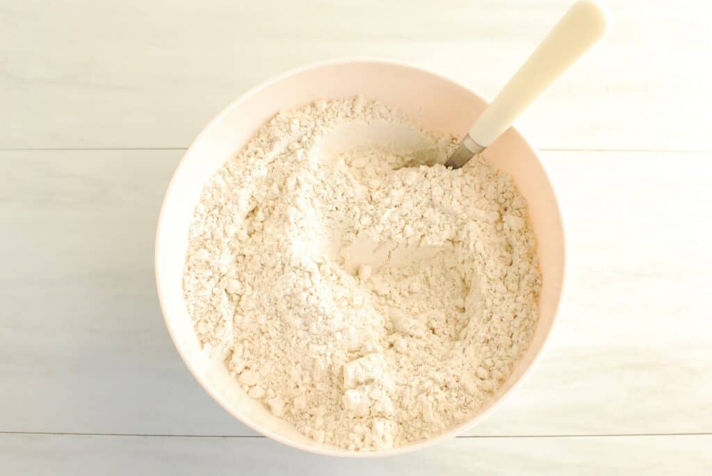 Flour, salt, baking powder, baking soda, and pumpkin spice mixed together in a bowl.