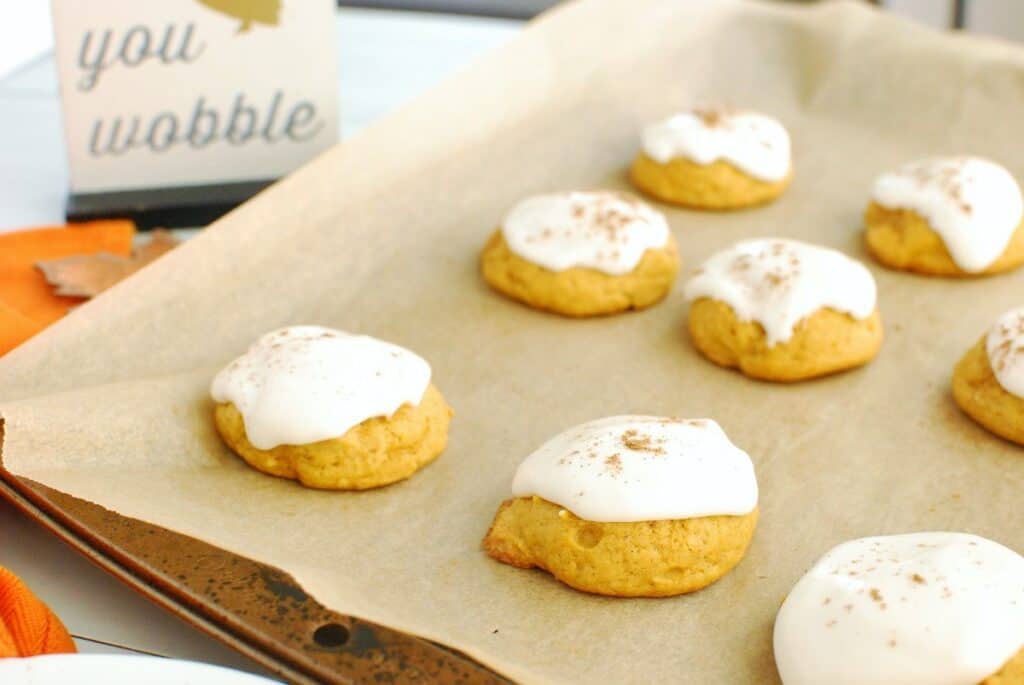 Dairy free pumpkin cookies with cream cheese frosting on a baking sheet.