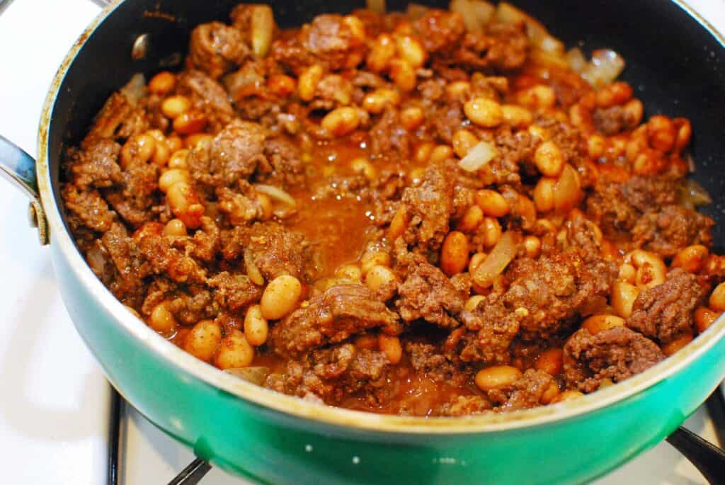 Ground beef, onion, beans, and taco seasoning in a sauté pan.