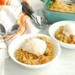 A bowl with dairy free apple crisp topped with dairy free vanilla ice cream.