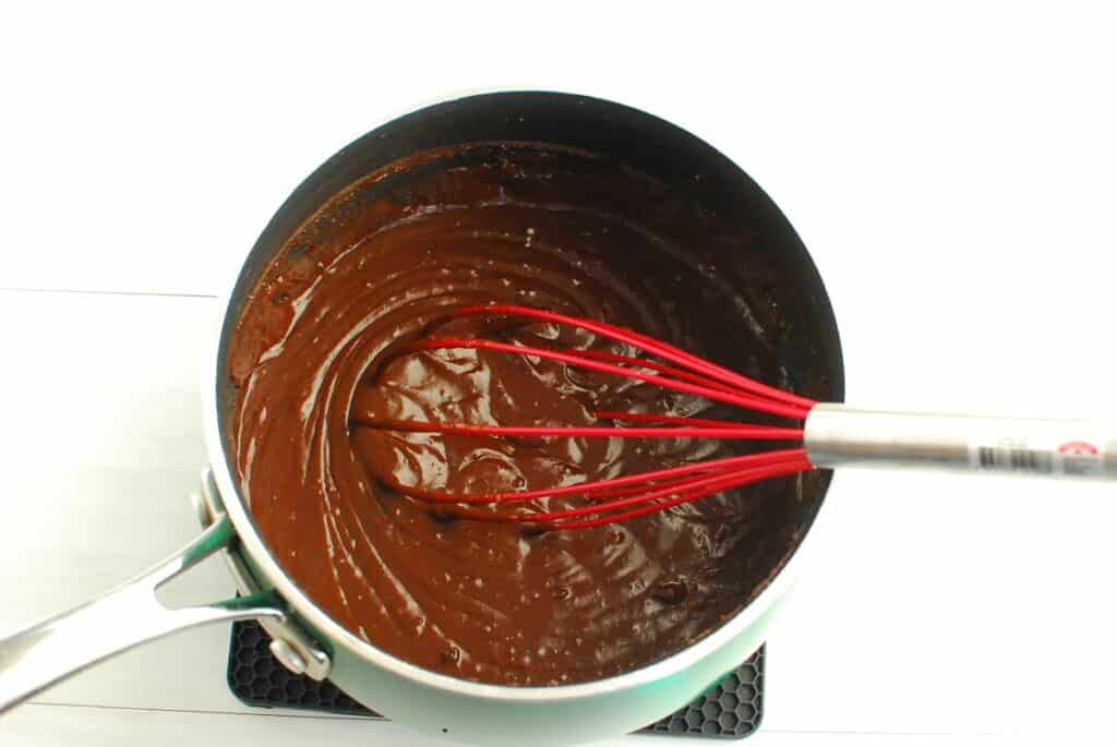Chocolate pie filling in a pot with a whisk.