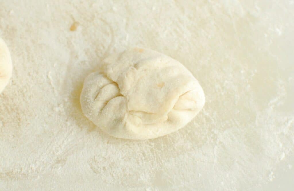 The edges of the dough are sealed together to form a ball.