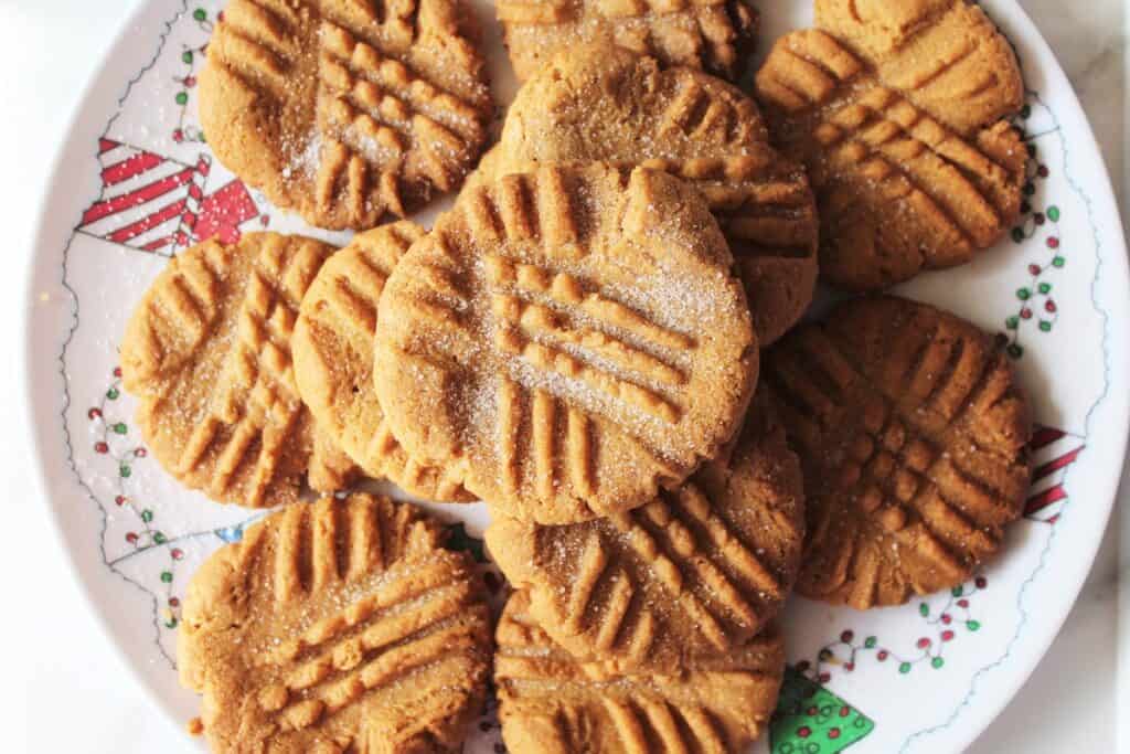 A plate full of dairy free peanut butter cookies with a crisscross pattern.