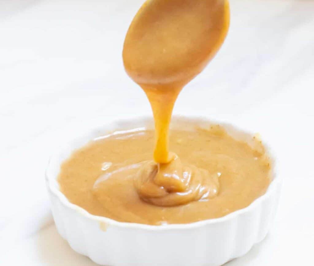 A spoon with date caramel dip dripping off.