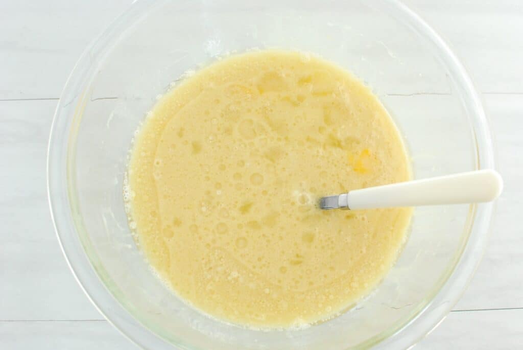 Eggs, oil, sugar, almond milk, dairy-free yogurt, and vanilla whisked together in a mixing bowl.