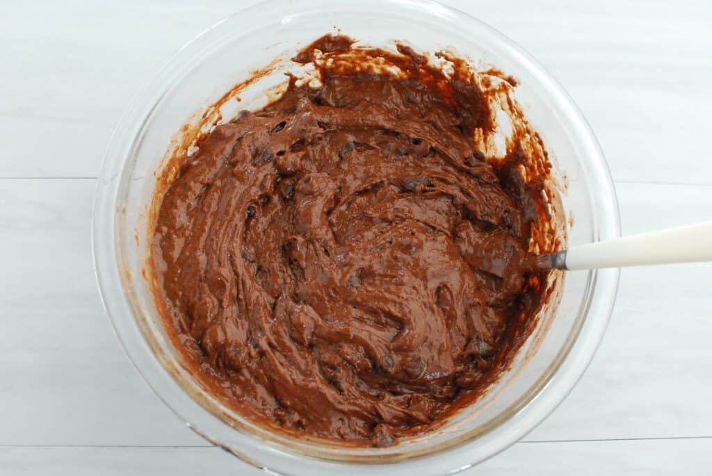 Chocolate muffin batter in a mixing bowl with chocolate chips folded in.