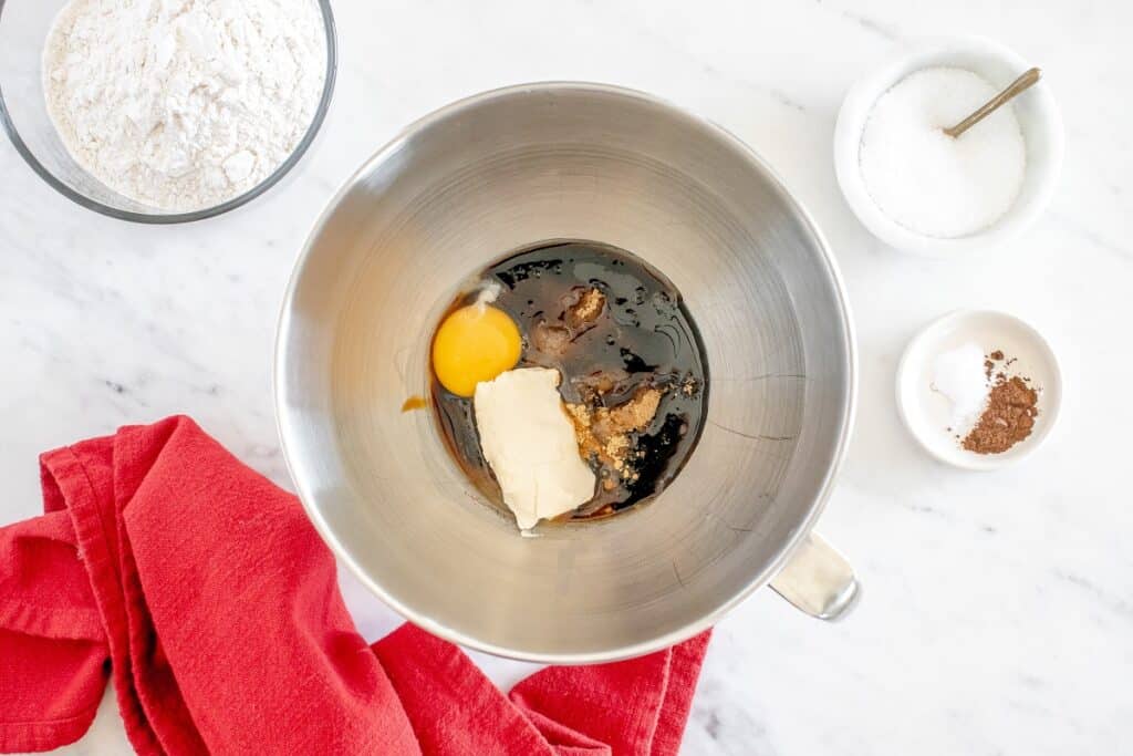 Dairy free butter, molasses, brown sugar, egg, and spices added to a mixing bowl.