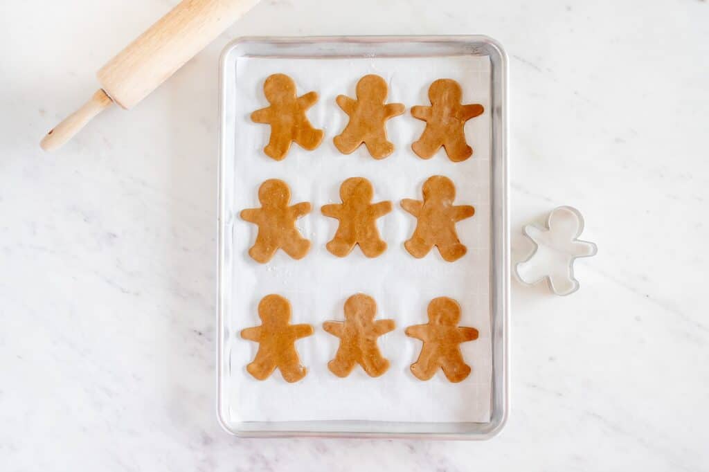 Unbaked gingerbread cookies on a parchment-lined baking sheet.