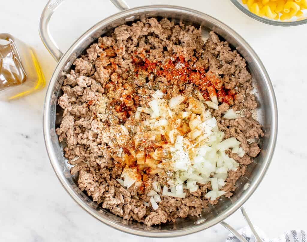 Sauté pan filled with ground beef, onion, and seasonings.