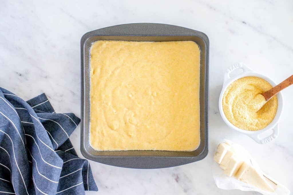 Raw cornbread batter in an 8x8 dish.