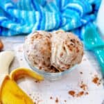 Dairy free banana ice cream with chocolate sunflower butter swirl and crushed cookies on top in a glass serving bowl.