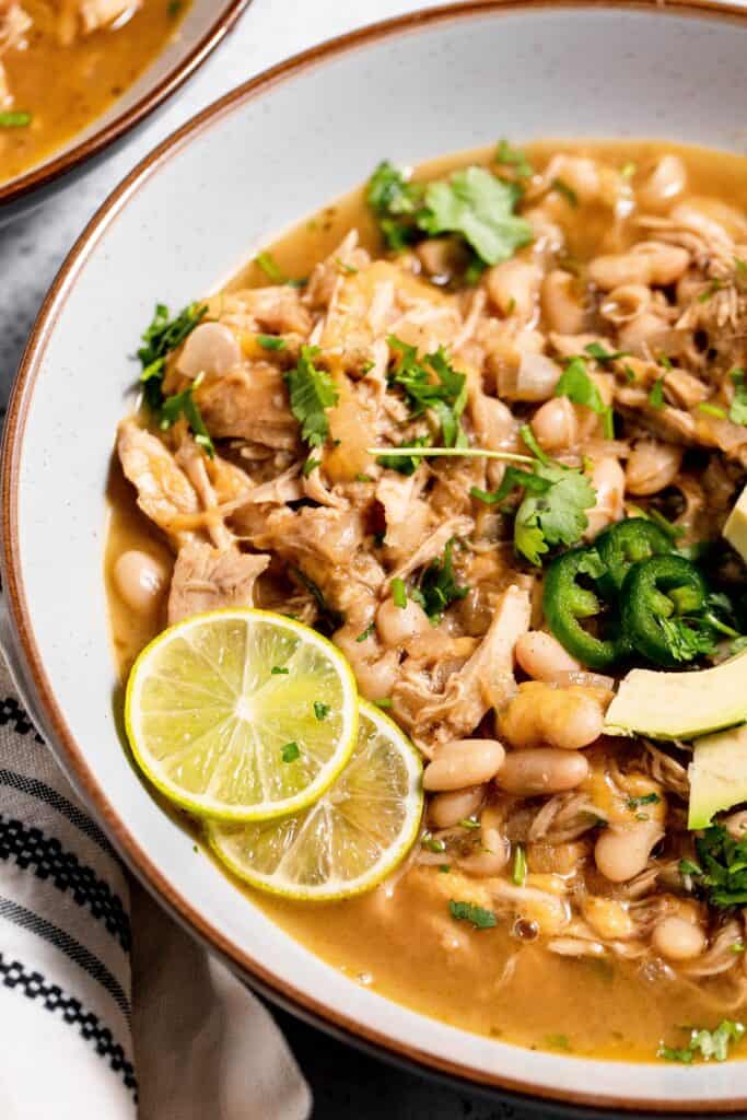 A close up of a bowl of dairy free white chicken chili garnished with lime slices.