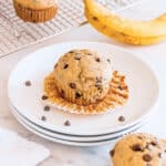 A dairy free banana muffin on a white plate with the muffin wrapper pulled down.