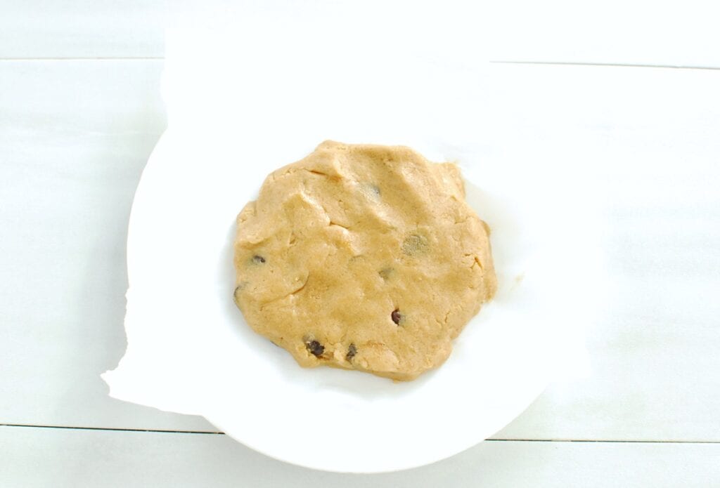 Cookie dough formed in a disc on a parchment lined plate.