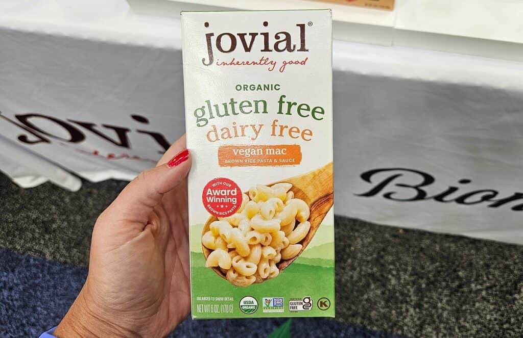 A woman's hand holding a box of Jovial gluten free dairy free mac and cheese.
