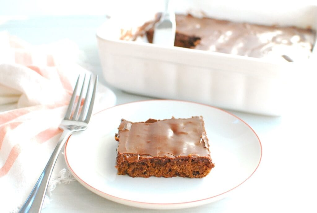 A dairy free brownie on a plate with the baking dish of brownies in the background.