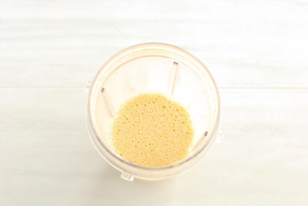 Eggs, dairy free eggnog, cinnamon, vanilla, and flour mixed together in a blender cup.
