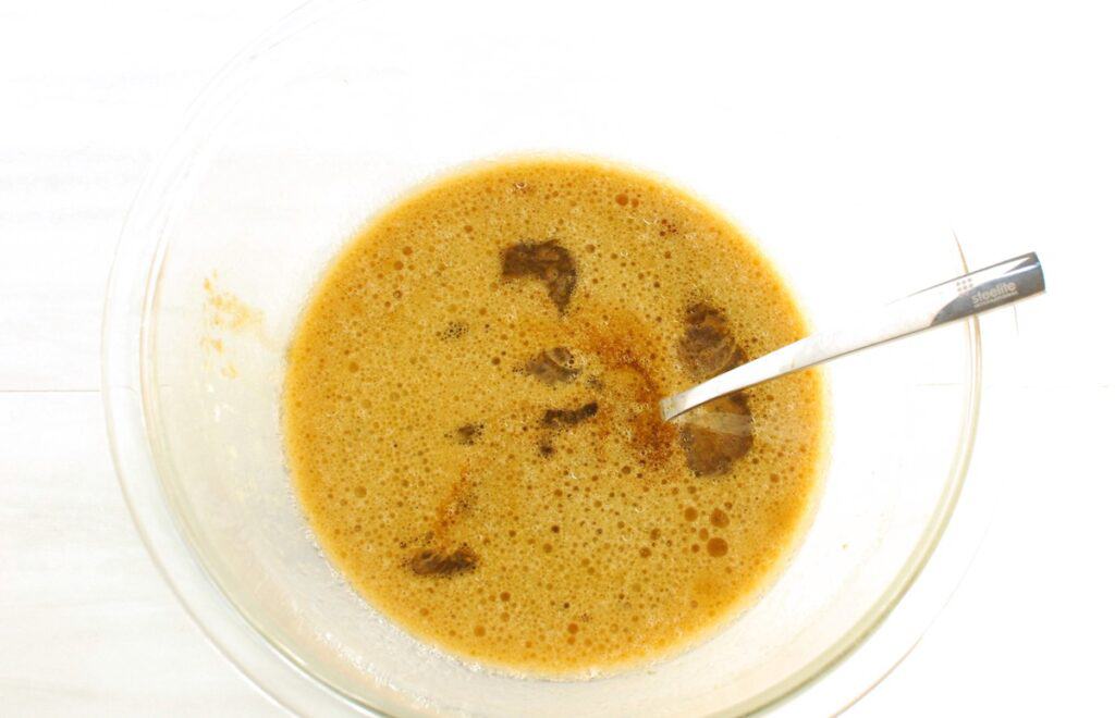 Oil, almond milk, brown sugar, molasses, egg, and vanilla extract mixed in a glass bowl.