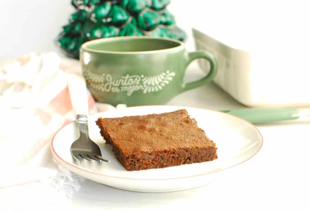 A dairy free gingerbread brownie next to a mug with oat milk.